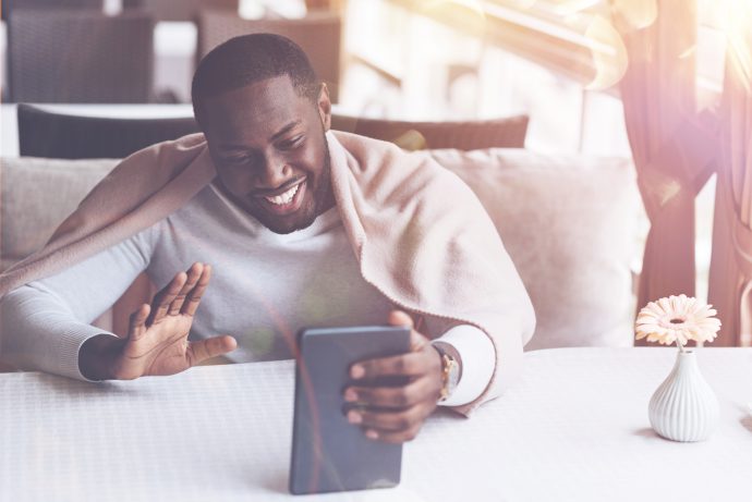 man smiling and waving at phone