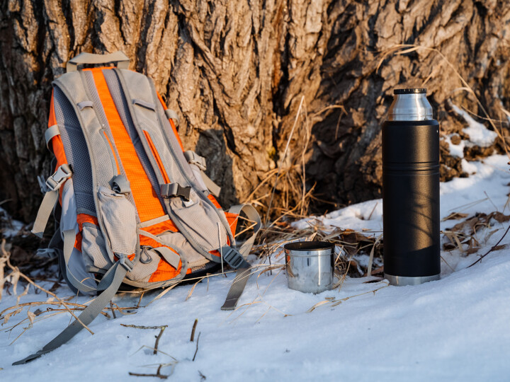 backpack and thermos near a tree in the snow