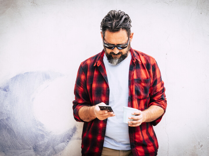 man wearing red plaid shirt holding phone