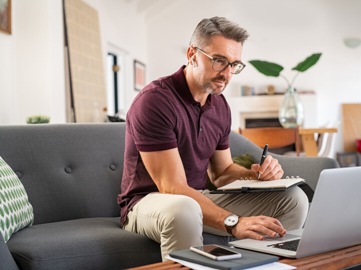 business man writing and typing on laptop