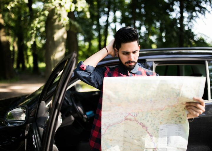 lost traveler outside car holding map