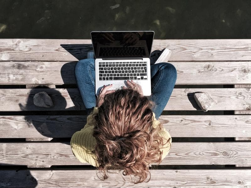 person on laptop sitting on bench