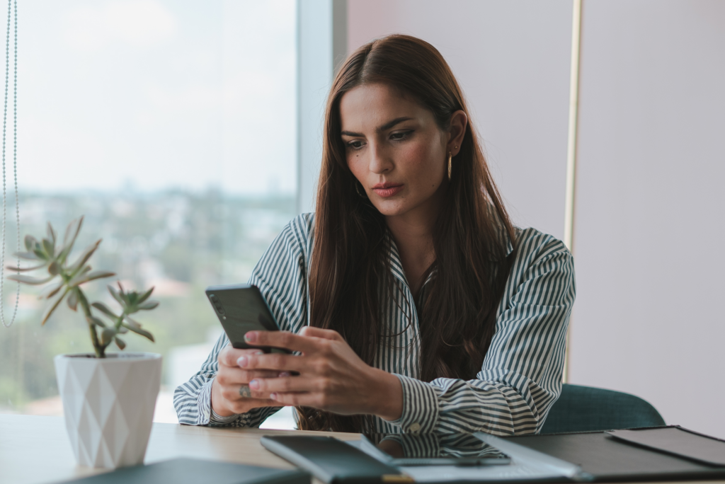 brunette looking at phone in office setting