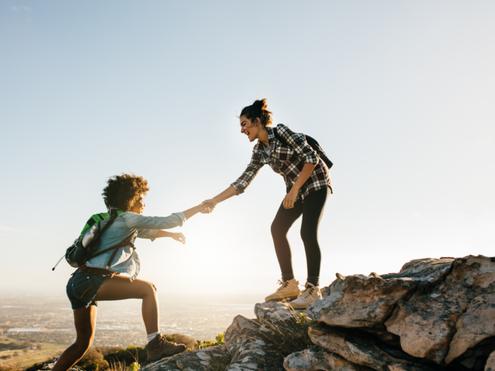 friends helping each other up mountain