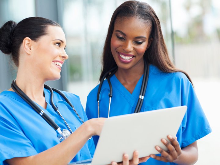 two nurses looking a a laptop and smiling