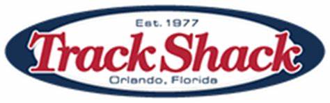 Logo for Track Shack, established 1977, Orlando, Florida, featuring red and blue text inside an oval, celebrating community impact and giving back.