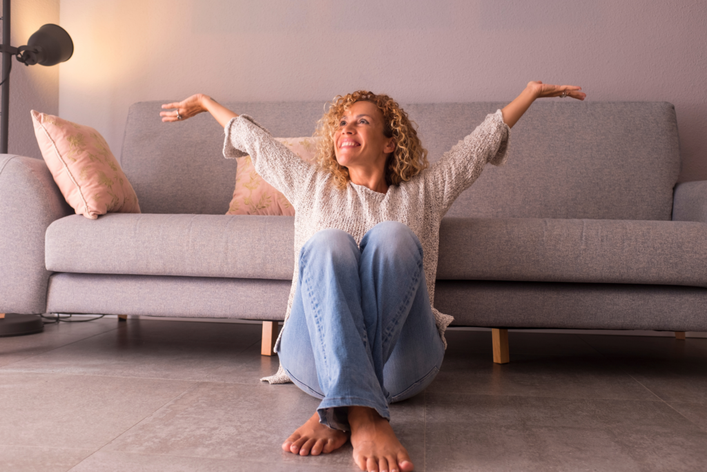 happy woman sitting on floor with arms raised