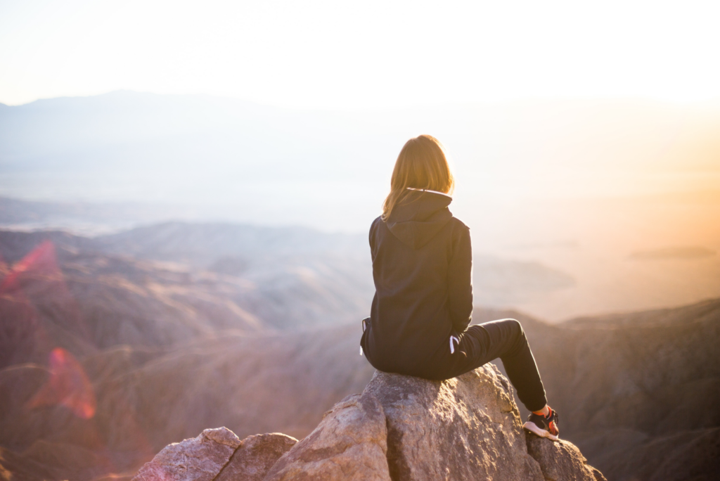 woman sitting on a rock looking out at the horizon