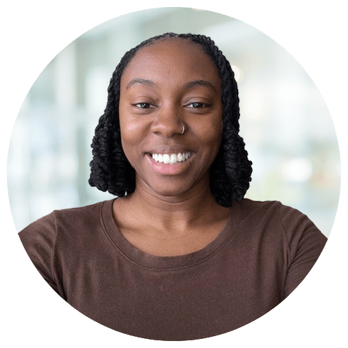 Andrea (Drea) DuPree - National Recruiter at Jackson Nurse Professionals, with braided hair and a nose ring, wears a brown top and smiles at the camera against a blurred light background.