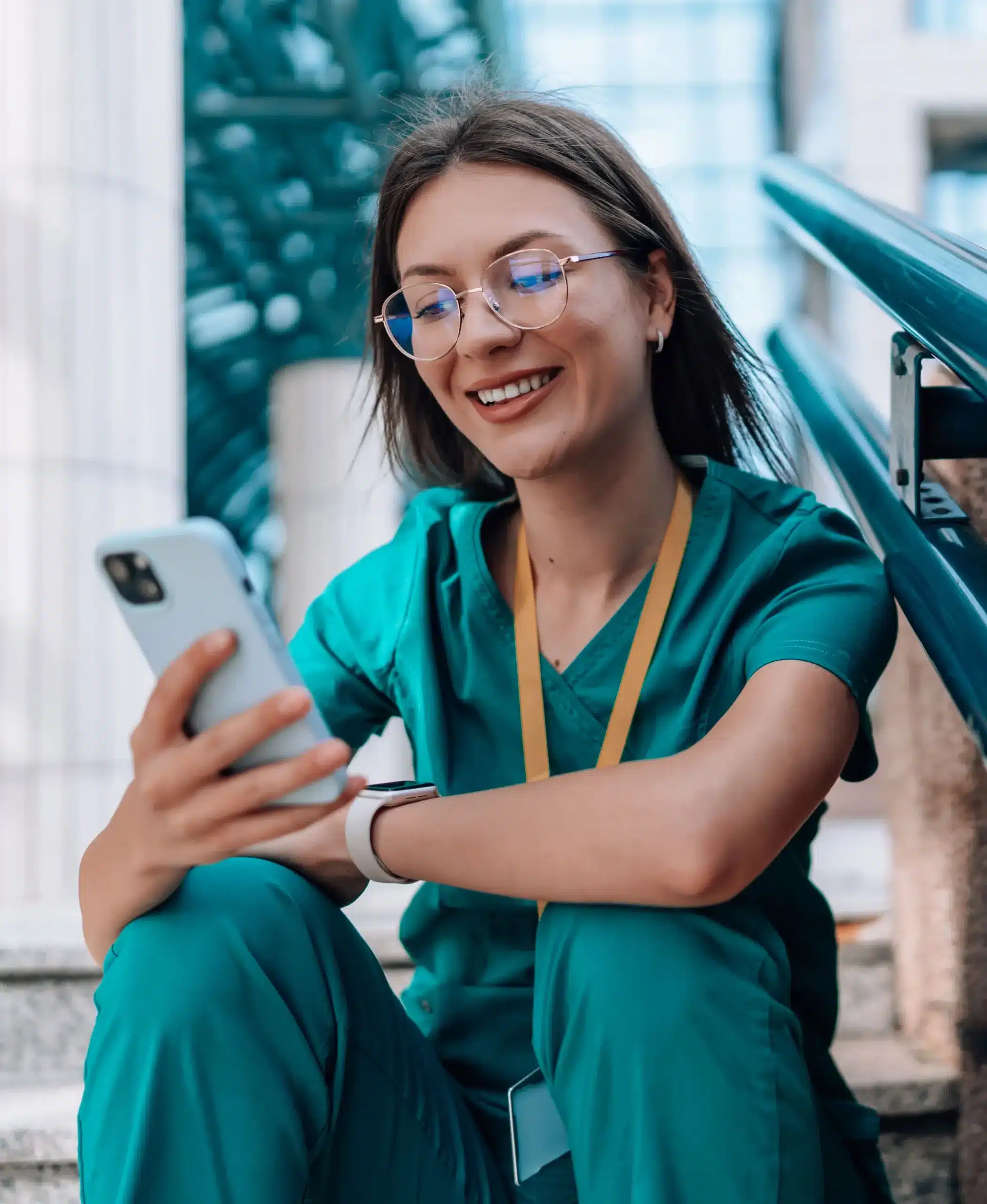 a female nurse sitting outside on stairs looking on her mobile phone