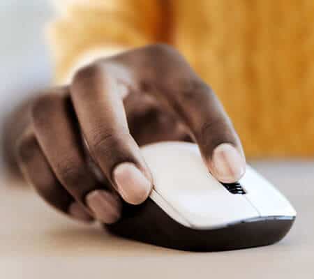African American hand on mouse next to a laptop