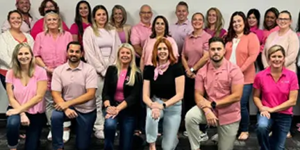 Group of people posing together indoors while wearing various shades of pink.